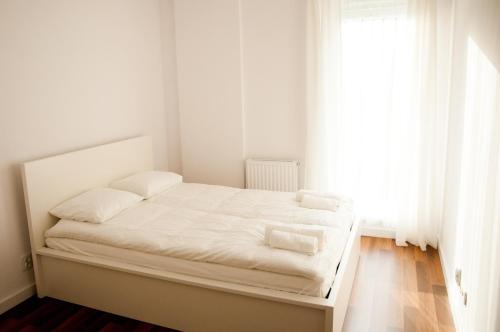 罗兹Apartament Blu的白色的卧室配有白色床单和窗户