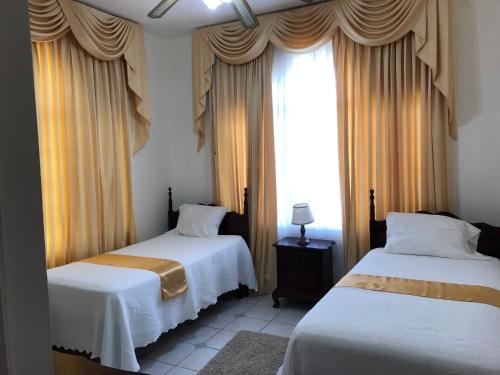欧丘里欧GoldenView Guesthouse Ocho Rios的一间卧室设有两张床,窗户配有窗帘