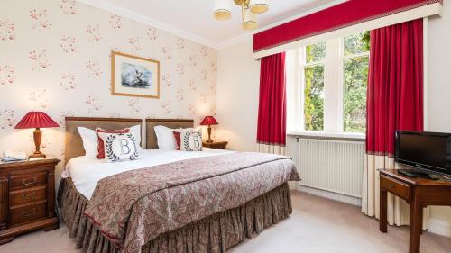 珀斯巴拉蒂斯之家酒店的一间卧室配有一张带红色窗帘的床和电视。