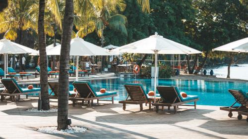 弗利康弗拉克金沙套房度假和Spa酒店的一组椅子和遮阳伞,位于游泳池旁