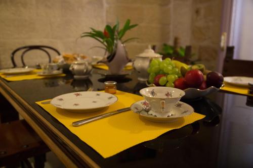 莱切玛兰尼欧住宿加早餐旅馆的一张桌子,上面放两个盘子和一碗水果