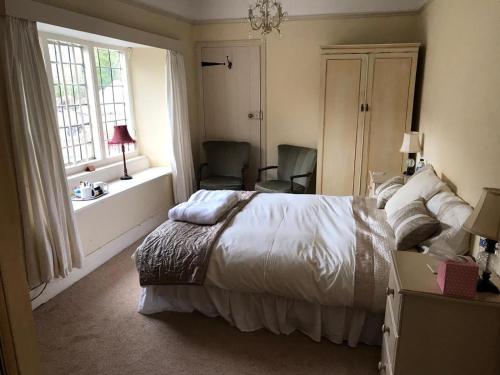 汤顿The Carew Arms的一间卧室配有一张床、两把椅子和一个窗户