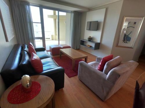 开普敦Lagoon Beach Hotel Apartments的客厅配有沙发、椅子和桌子