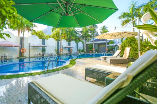 岘港Eden Plaza Da Nang Hotel的度假村旁的游泳池配有椅子和遮阳伞