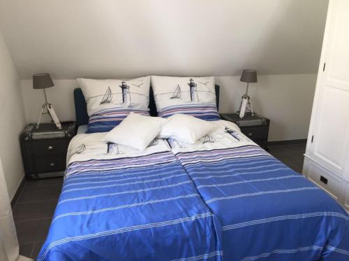 格洛韦Reethaus Seeadler mit Sauna, Terrasse, Garten的一张带蓝色和白色床单及枕头的床
