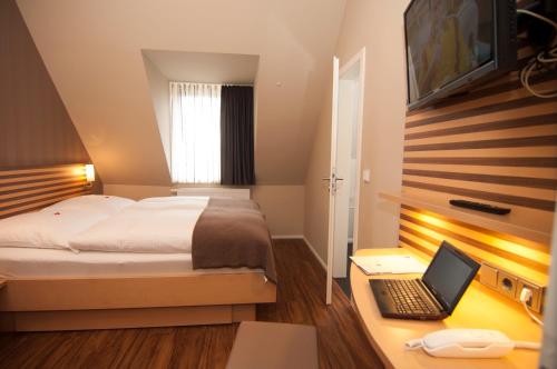 曼海姆奥克森宾馆的一间卧室配有一张床和一张桌子上的笔记本电脑