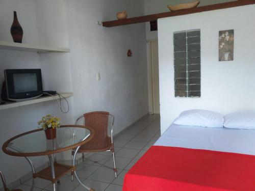 维索萨-杜塞阿拉Flat Matriz的一间卧室配有一张床、一张桌子和一台电视。