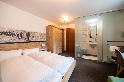 圣安东阿尔贝格加姆伯格酒店的一间带白色大床的卧室和一间浴室