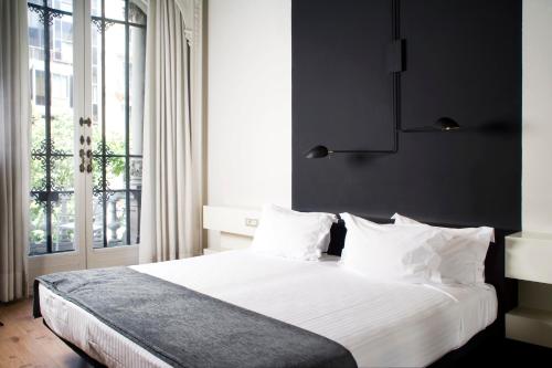 巴塞罗那兰布拉普拉提克酒店的一间卧室配有一张带白色床单的床和一扇窗户。