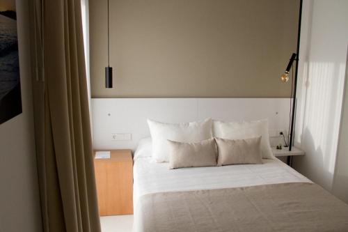 马萨龙港Sosiego Hostal de Mar的一间卧室配有带白色床单和枕头的床。