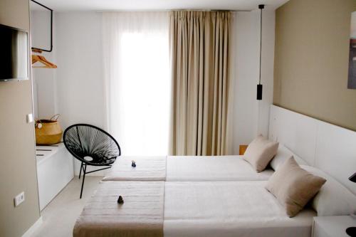 马萨龙港Sosiego Hostal de Mar的酒店客房设有两张床和窗户。