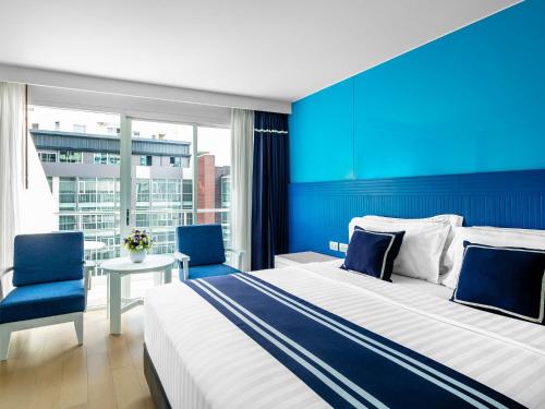 芭堤雅市中心A1新翼酒店的酒店客房设有一张大床和两张蓝色椅子。