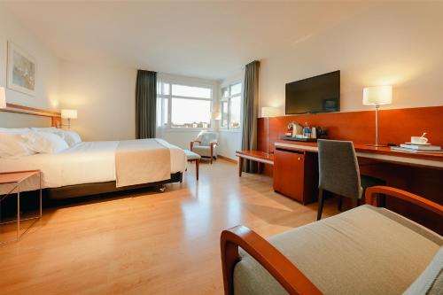 毕尔巴鄂Abba Euskalduna Hotel的配有一张床和一张书桌的酒店客房