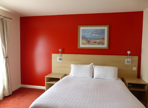 罗瑟勒姆迎宾罗瑟勒姆/谢菲尔德酒店的卧室设有红色的墙壁和一张床