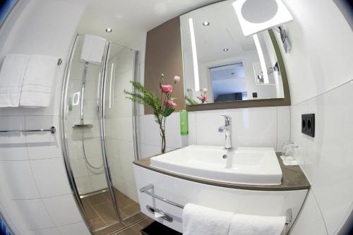 弗莱堡Boutiquehotel am Stadtgarten的一间带水槽、淋浴和镜子的浴室