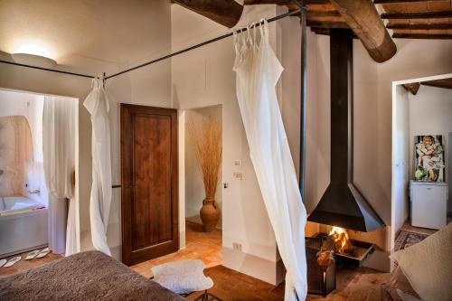 蒙特普齐亚诺Podere Poggio al sole的一间卧室配有一张带白色窗帘的床和壁炉
