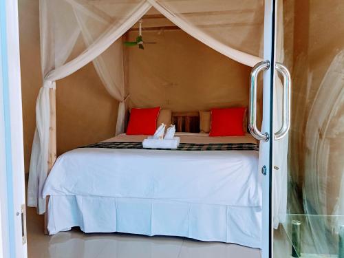 新加拉惹Sekumpul BnB的卧室配有带红色枕头的白色床