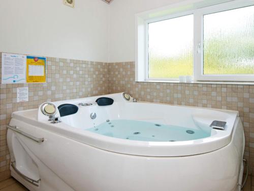 海默特8 person holiday home in Tarm的带窗户的浴室内的白色浴缸