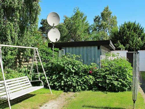 Strøby Egede4 person holiday home in K ge的坐在花园旁的草上的一个白色长凳