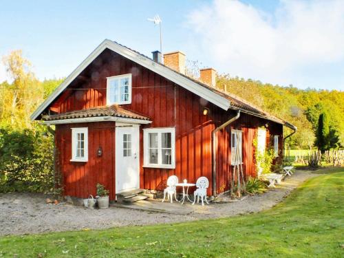 Västra Tunhem8 person holiday home in Varg n的红色的房子,配有两把椅子和一张桌子