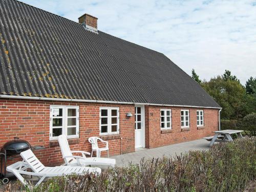 托弗图姆5 person holiday home in R m的红砖房子,配有白色椅子和烧烤架
