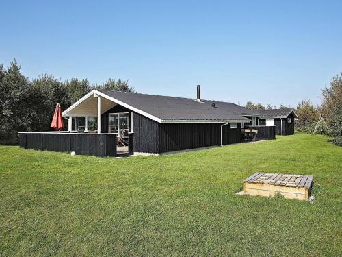 伦斯楚普8 person holiday home in Hj rring的一座带草地庭院的黑色房子