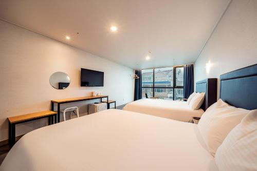 西归浦市Sunrise Hotel Supjikoji的酒店客房设有两张床和电视。
