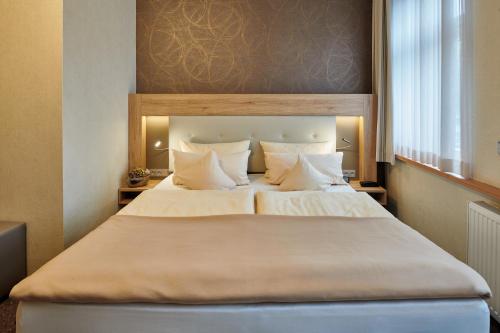 盖尔森基兴祖姆施万安姆比恩特酒店的卧室配有一张带白色床单和枕头的大床。