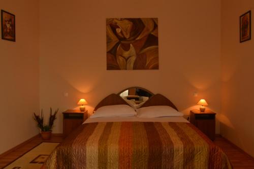 特尔古穆列什Pensiunea Kenza的一间卧室配有一张带两盏灯和一幅画的床铺
