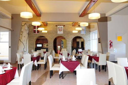 Macachín尤兹克阿尔卡塔苏娜酒店的餐厅配有白色桌椅和红色桌布