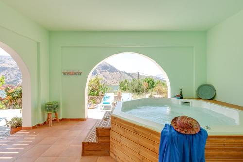 KávallosVilla Kallisti - Artemis的大型浴室设有热水浴缸和2扇拱形窗户