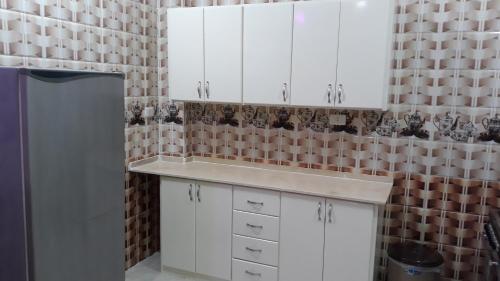 卢克索Isis Flats的厨房配有白色橱柜和瓷砖墙