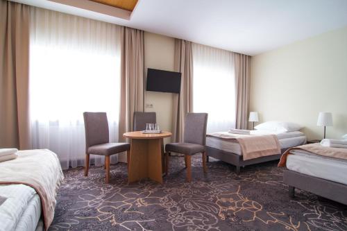 Pomiechówek兹贾德芒谷利亚酒店的酒店客房带两张床和一张桌子以及椅子。