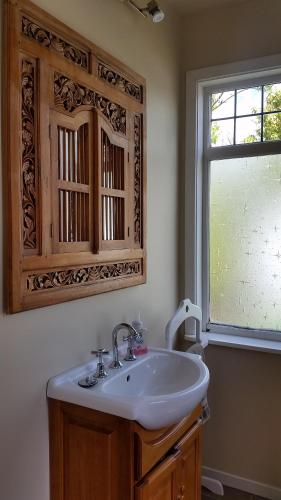 基督城设计师小屋的一间带白色水槽和窗户的浴室