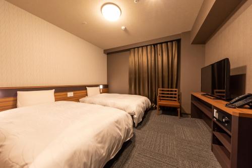 川崎Dormy Inn Kawasaki Natural Hot Spring的酒店客房设有两张床和电视。