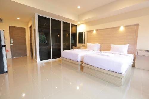 南邦Lampang Residence的大房间设有两张床铺和玻璃墙