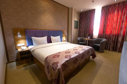 塔什干塞亚悠酒店的配有一张床和一把椅子的酒店客房