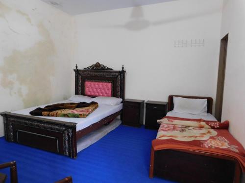 BālākotHamaliya Hotel & Restaurant的蓝色地板客房的两张床
