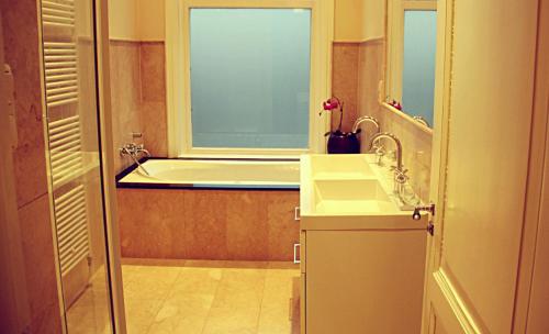 海牙印度支那庄园酒店的带浴缸、水槽和窗户的浴室