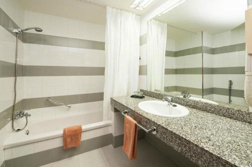 卡门港奥利维亚休闲酒店的一间带水槽、浴缸和镜子的浴室