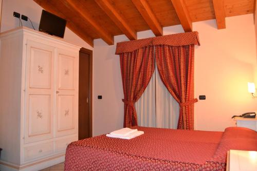 Ghedi阿尔伯格皮亚纳酒店的一间卧室设有红色的床和窗户。