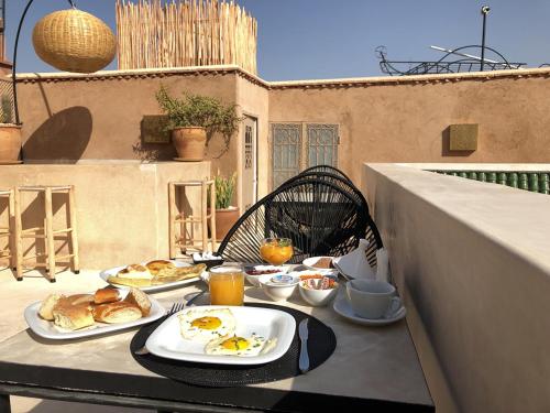 马拉喀什Riad Bamboo Suites & Spa的阳台上的一张桌子上放着两盘食物
