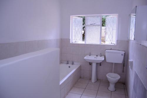 哈拉雷Royal Guest House的带浴缸水槽和卫生间的浴室