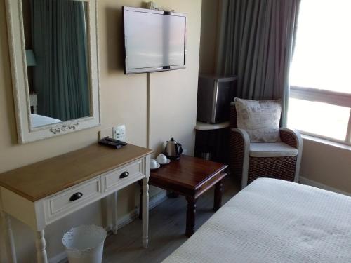 斯特兰德Sunset 786 Holiday Accom-212的酒店客房配有一张床、一张书桌和一台电视。