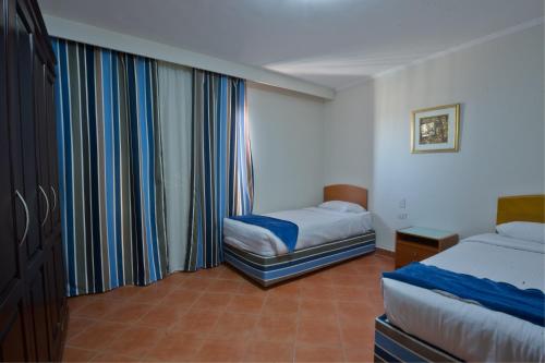 艾因苏赫纳Porto Sokhna Pyramids Apartments By Amer-Group的酒店客房设有两张床和窗户。