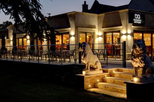 唐克斯特Best Western Premier Doncaster Mount Pleasant Hotel的两座狗雕像,坐在建筑物前面的台阶上