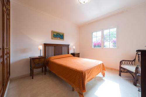 马斯帕洛马斯Villa Cosmos chalet con gran piscina y jardin privado的卧室配有床、椅子和窗户。