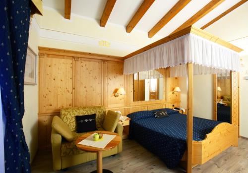 莫尔韦诺多洛米蒂山亚历山大康体酒店的一间卧室配有一张床、一张沙发和一张桌子