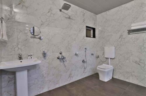 MundraHOTEL CENTRE POINT的白色的浴室设有水槽和卫生间。