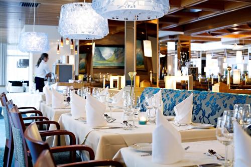 卢恩Hotel Alexandra Loen的用餐室配有白色桌椅和吊灯。